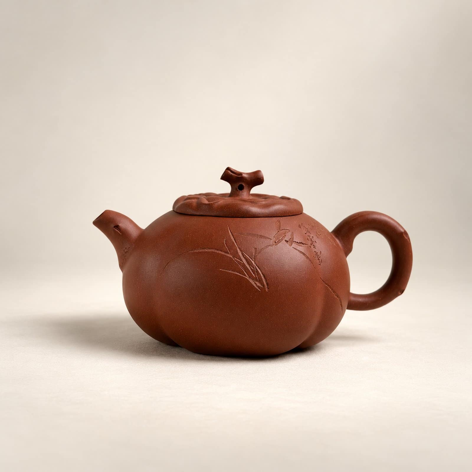 Reddish-brown teapot with a lobed body, bamboo-like carving and a branch-shaped lid knob.